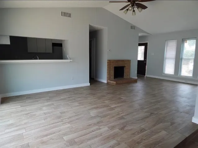 an empty room with wooden floor fireplace and windows