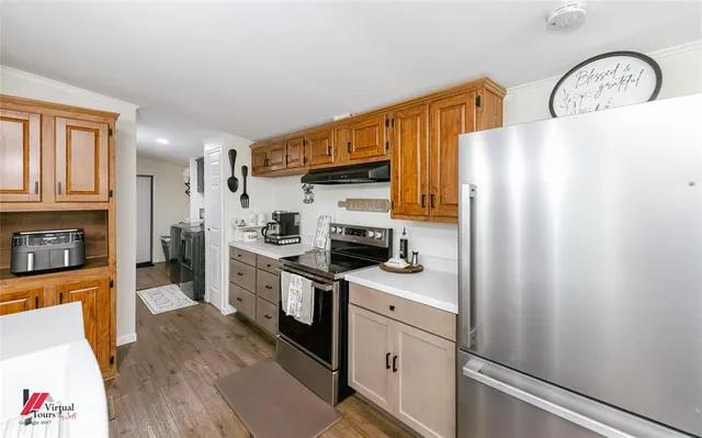 a view of a dining room and livingroom with furniture wooden floor a rug a flat screen tv a painting and a chandelier