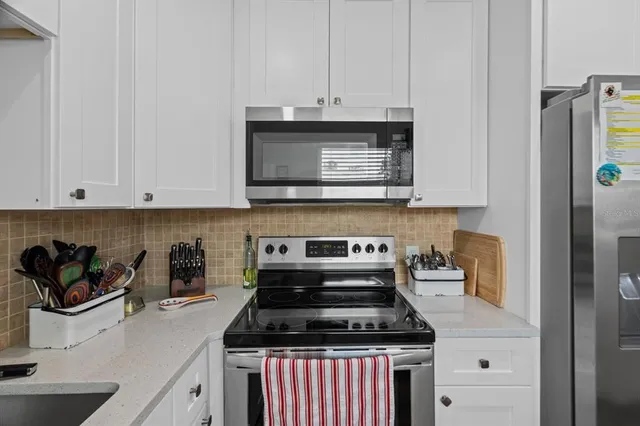 a kitchen with granite countertop stainless steel appliances and white cabinets