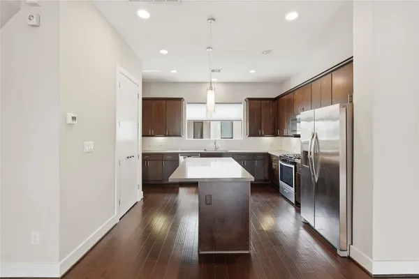 a large kitchen with a center island wooden floor stainless steel appliances and cabinets