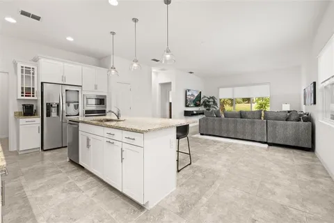 a kitchen with kitchen island granite countertop a sink a center island and stainless steel appliances