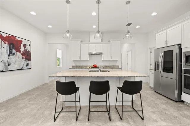a kitchen with stainless steel appliances granite countertop sink stove and white cabinets