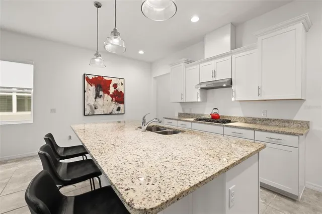 a kitchen with granite countertop a sink a stove and cabinets