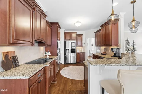 a kitchen with granite countertop stainless steel appliances a sink a stove cabinets counter space and wooden floor