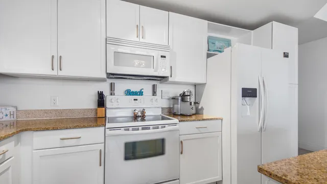 a kitchen with white cabinets and white appliances