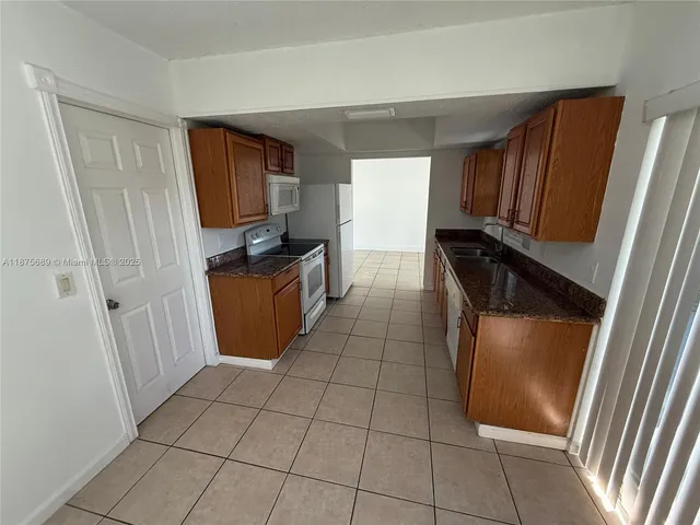 a kitchen with granite countertop a stove a sink a refrigerator and a window