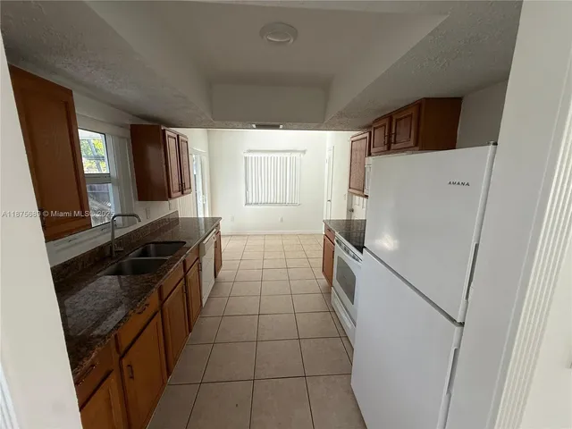a kitchen with a sink a stove top oven and cabinetry