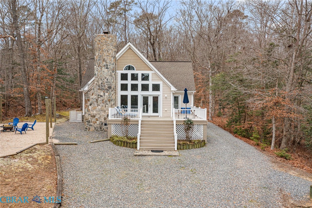 4775 Stormont Road Hartfield, VA 23071 - Photo 5 of 45 View of front of house with french doors, a deck, a chimney, view of scattered trees, and roof with shingles