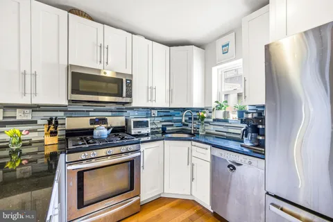 a kitchen with granite countertop a sink a stove and cabinets