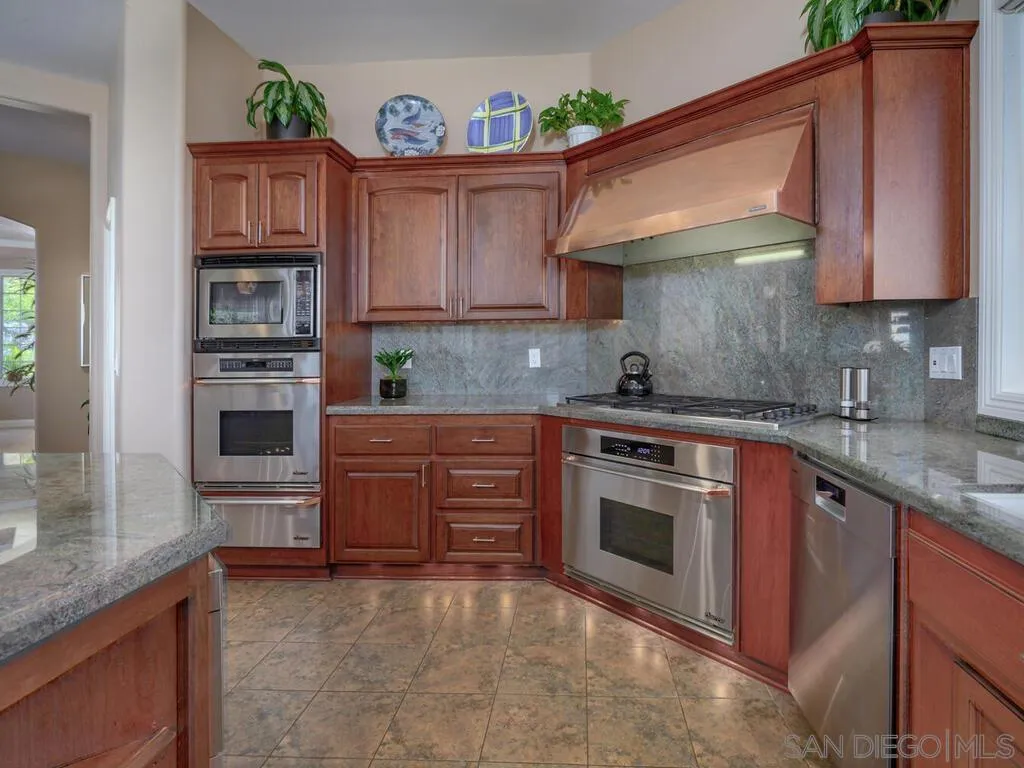 14490 Ridge Ranch Road Escondido, CA 92027 - Photo 13 of 74 a kitchen with stainless steel appliances granite countertop a stove top oven a sink and dishwasher a oven with wooden cabinets
