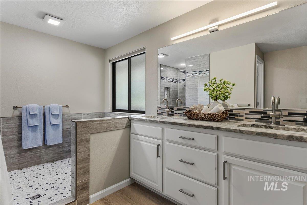599 Pebble Beach Way Eagle, ID 83616 - Photo 23 of 44 Dual vanity with undermount sinks, stone countertop, and an extended mirror