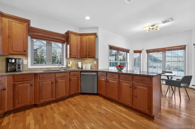 a kitchen with stainless steel appliances granite countertop wooden cabinets a stove a sink and a large window