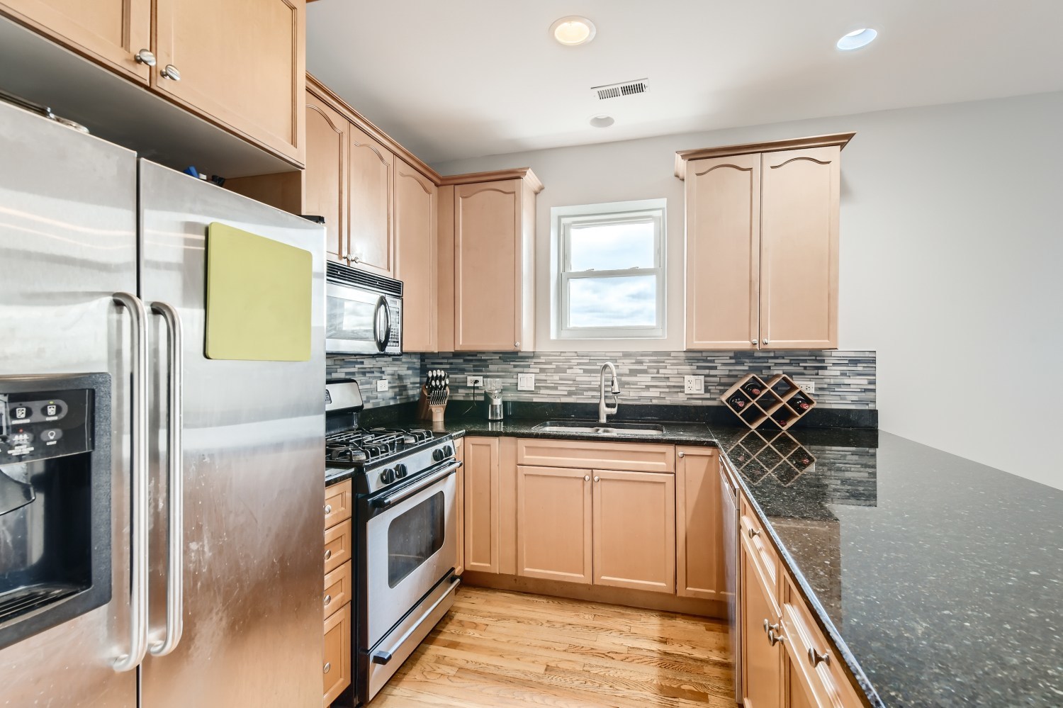 3114 West Irving Park Road, Unit 4E Chicago, IL 60618 - Photo 3 of 18 a kitchen with a sink cabinets stainless steel appliances and a window