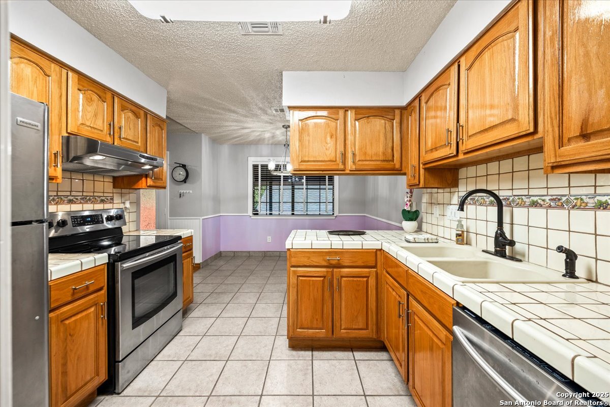 9308 Dover Ridge San Antonio, TX 78250 - Photo 13 of 41 a kitchen with stainless steel appliances granite countertop a sink and a stove