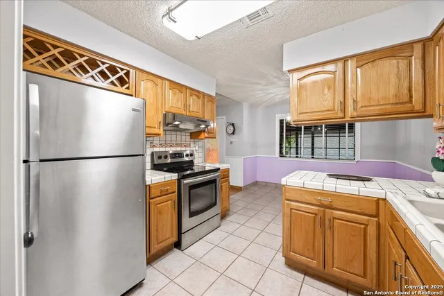 a kitchen with stainless steel appliances granite countertop a refrigerator a stove a sink and dishwasher
