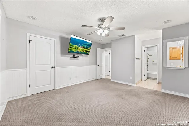 an empty room with windows and a ceiling fan