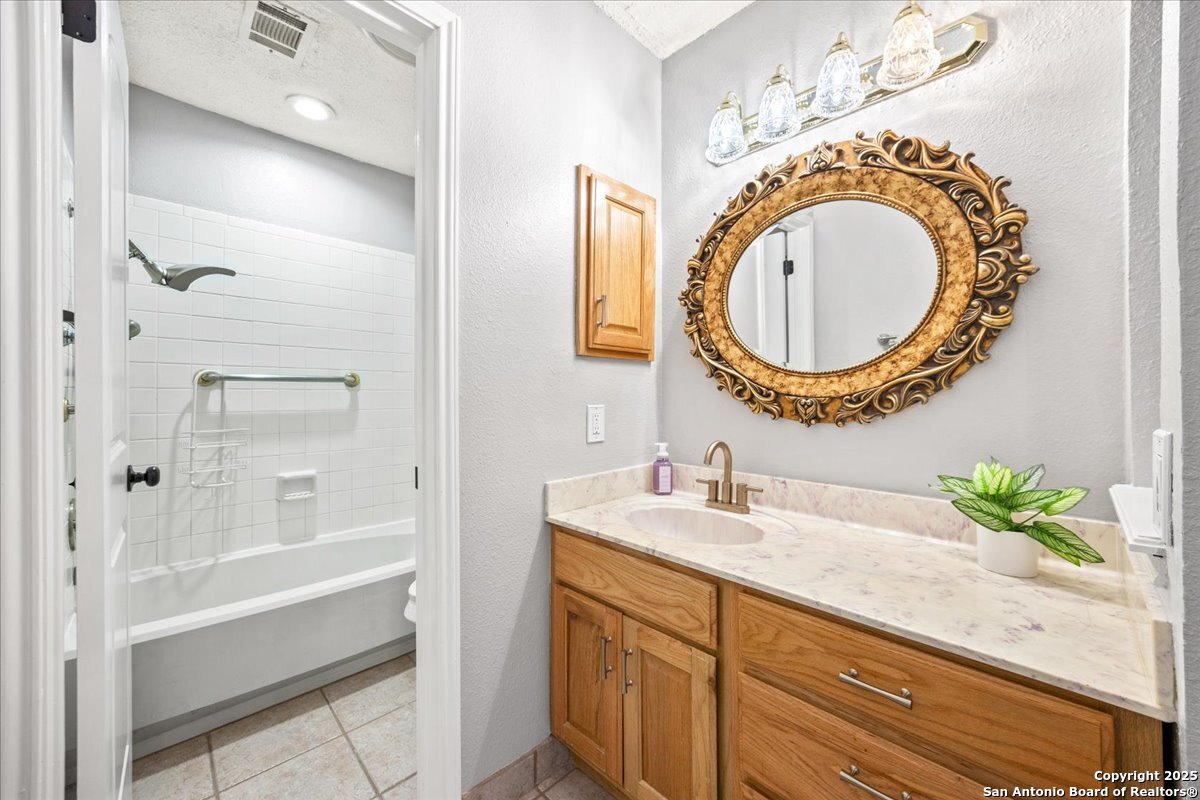 9308 Dover Ridge San Antonio, TX 78250 - Photo 19 of 41 a bathroom with a granite countertop sink a mirror and a shower