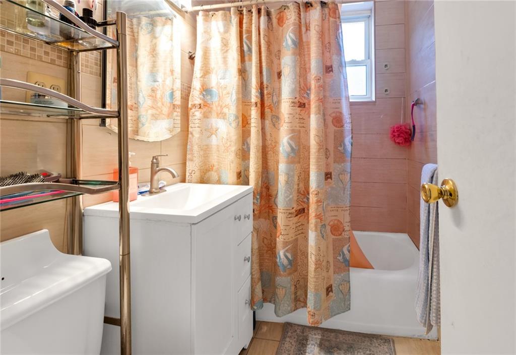 2155 82nd Street, Unit 5D Brooklyn, NY 11214 - Photo 16 of 19 a bathroom with a sink a toilet and shower curtain