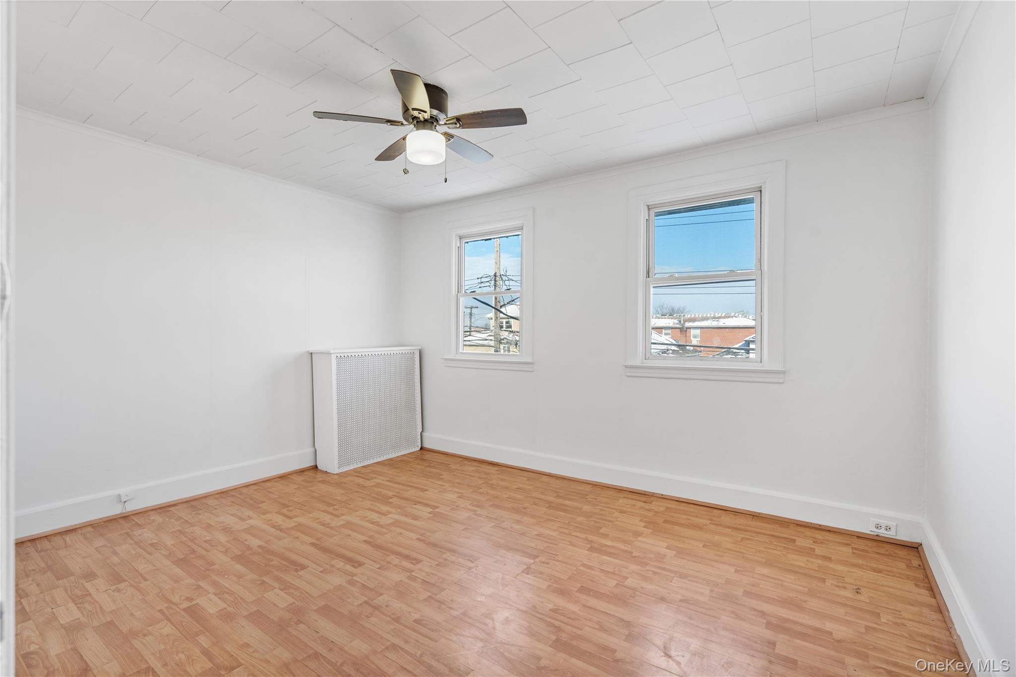 123-10 25th Road Queens, NY 11354 - Photo 14 of 27 Spare room with radiator, light wood-style floors, and a ceiling fan