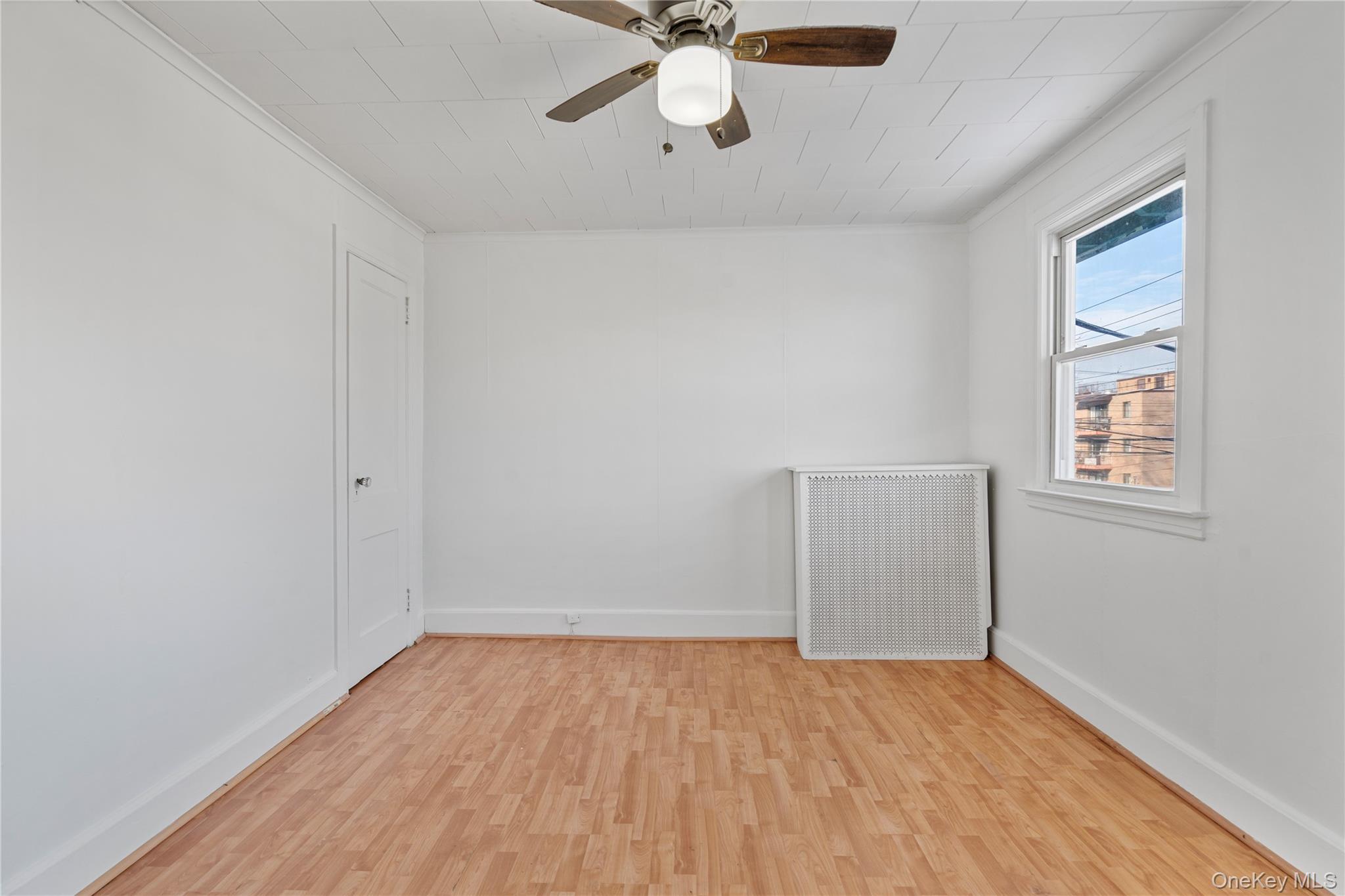 123-10 25th Road Queens, NY 11354 - Photo 15 of 27 Spare room with radiator heating unit, light wood-style floors, ceiling fan, and ornamental molding