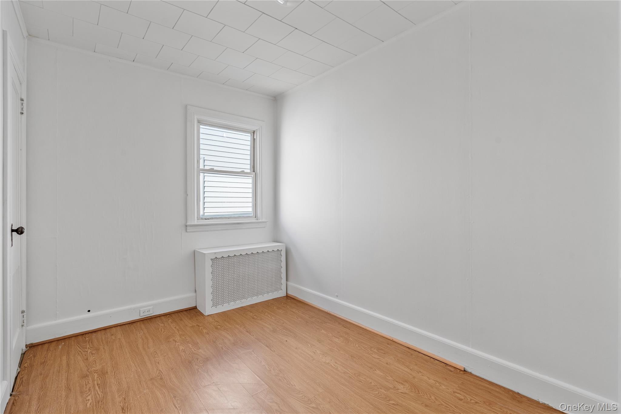 123-10 25th Road Queens, NY 11354 - Photo 17 of 27 Unfurnished room with radiator heating unit and light wood finished floors