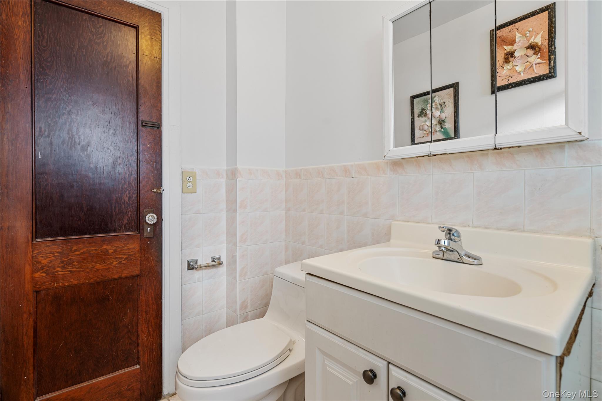 123-10 25th Road Queens, NY 11354 - Photo 22 of 27 Half bath with vanity, tile walls, and wainscoting