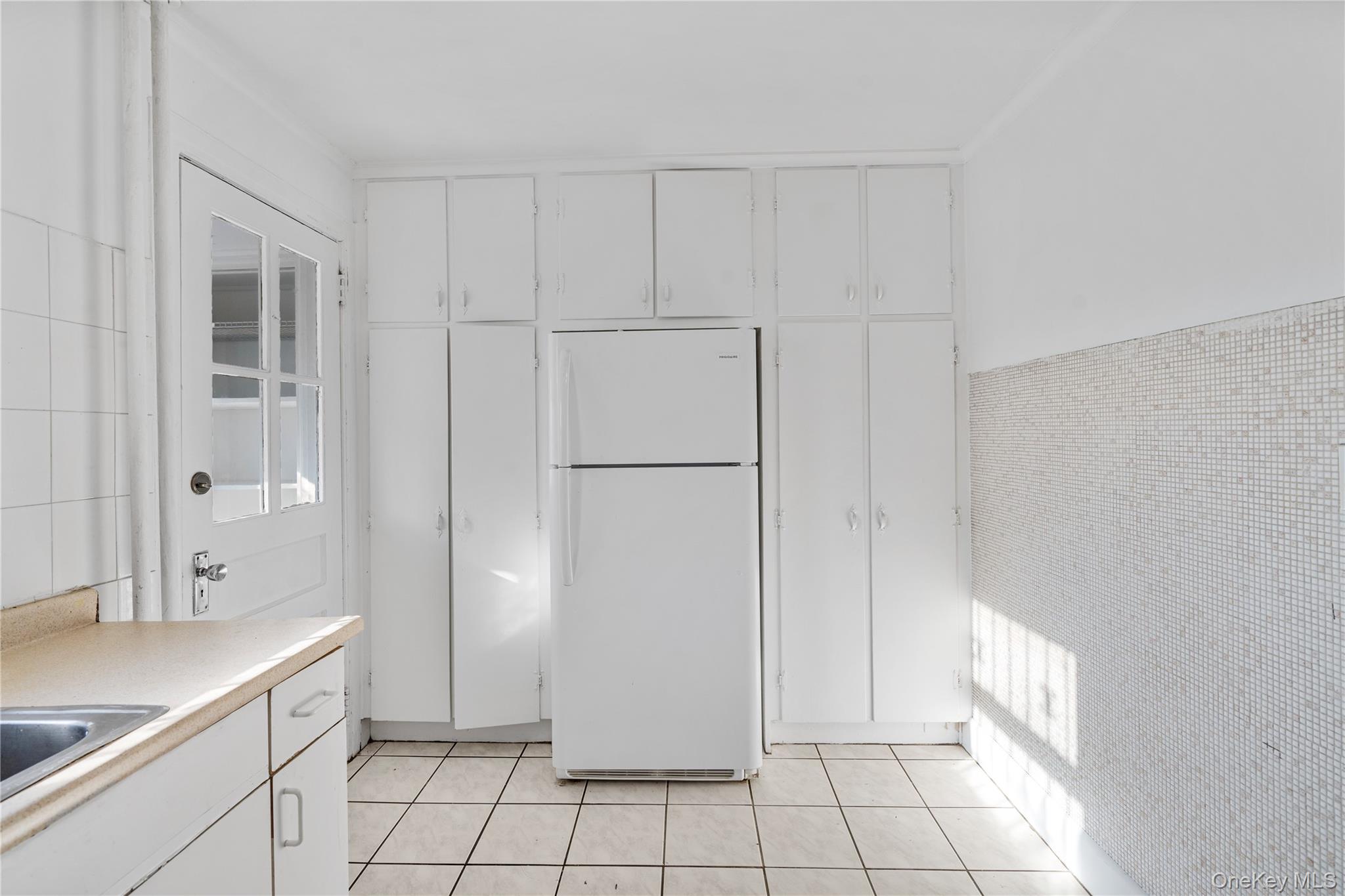 123-10 25th Road Queens, NY 11354 - Photo 6 of 27 Kitchen featuring white cabinetry, freestanding refrigerator, tile walls, light countertops, and light tile patterned flooring