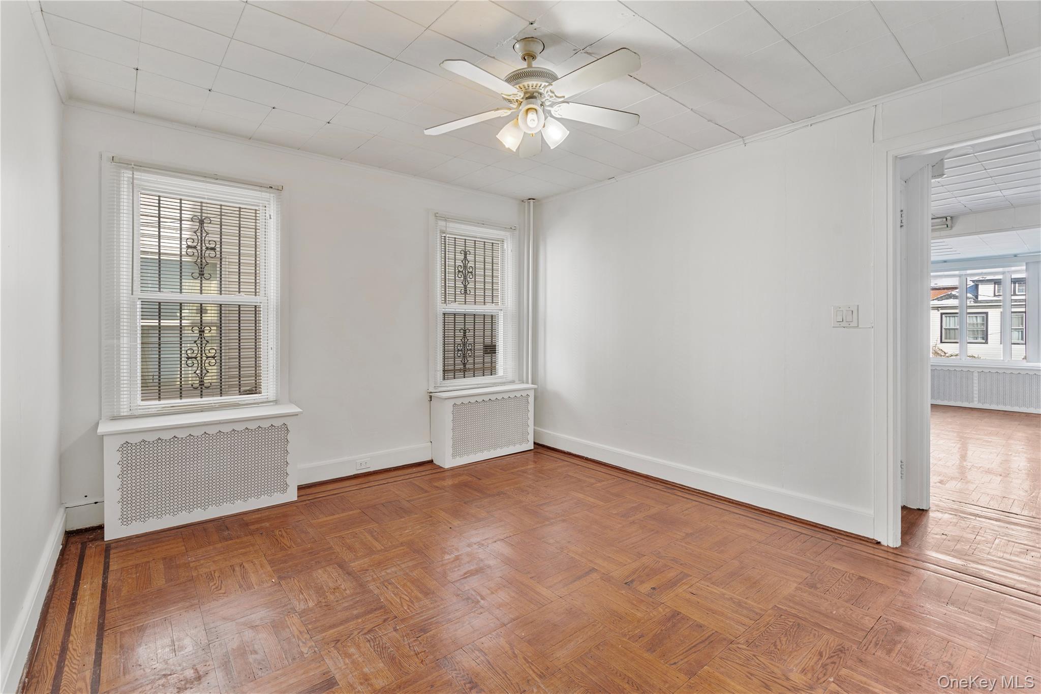 123-10 25th Road Queens, NY 11354 - Photo 7 of 27 Unfurnished room with radiator, a ceiling fan, parquet flooring, and healthy amount of natural light