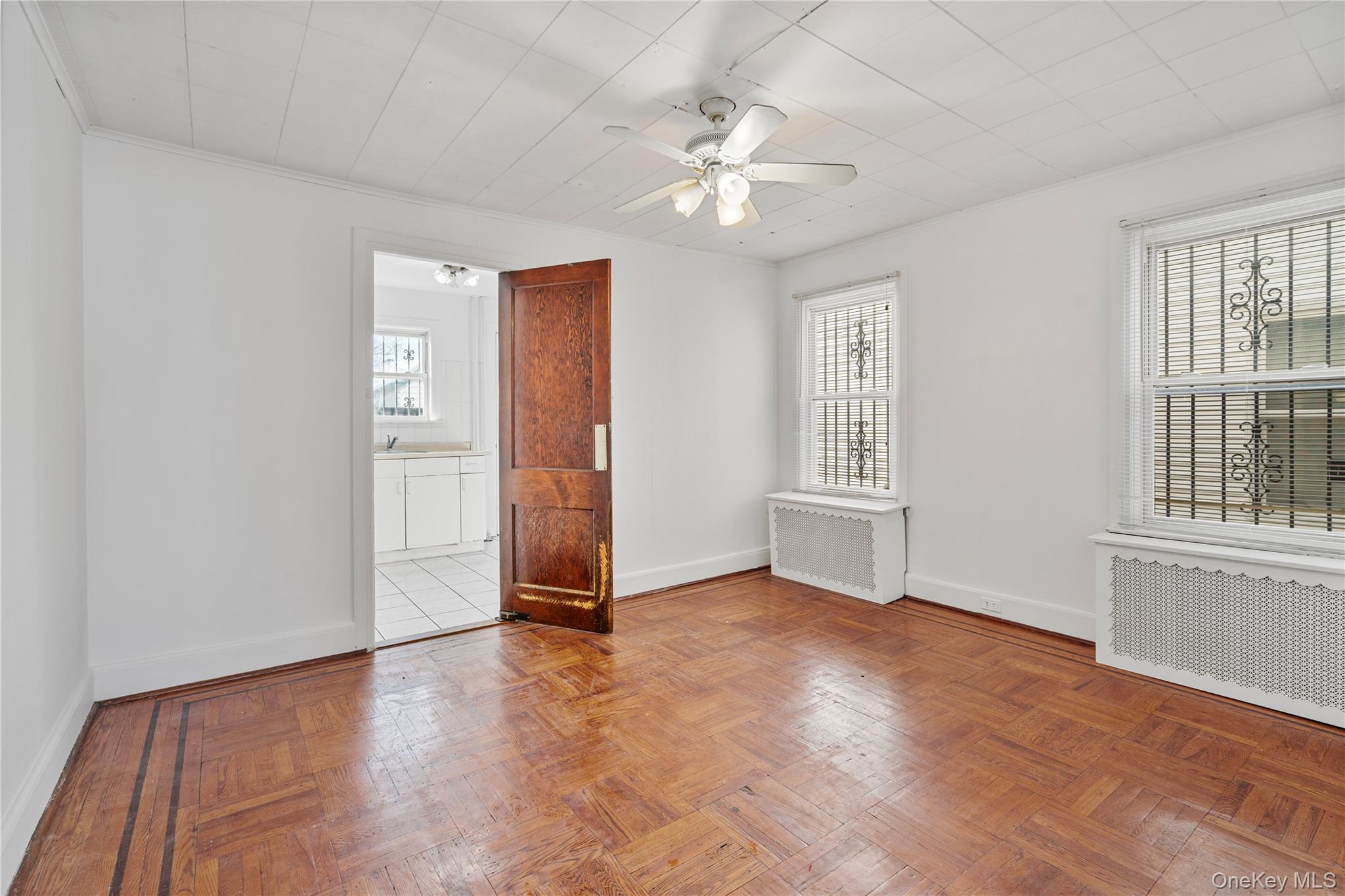 123-10 25th Road Queens, NY 11354 - Photo 8 of 27 Unfurnished room with radiator, a ceiling fan, parquet flooring, and healthy amount of natural light