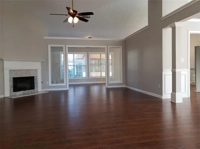 a view of an empty room with wooden floor fireplace and a window