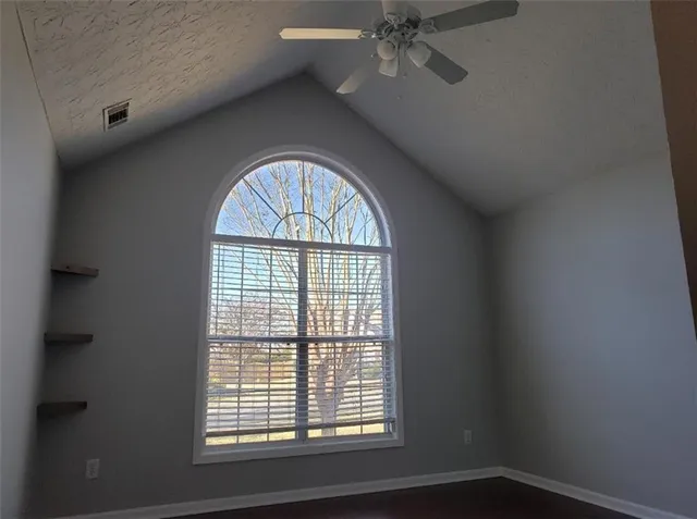 a view of empty room with wooden floor and fan
