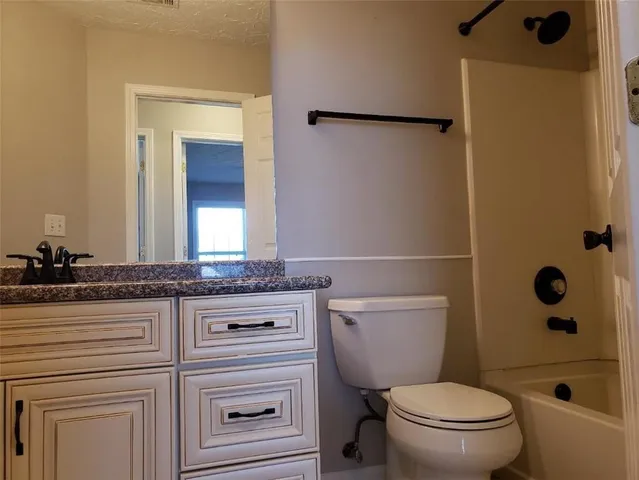 a bathroom with a granite countertop sink a toilet a mirror and shower
