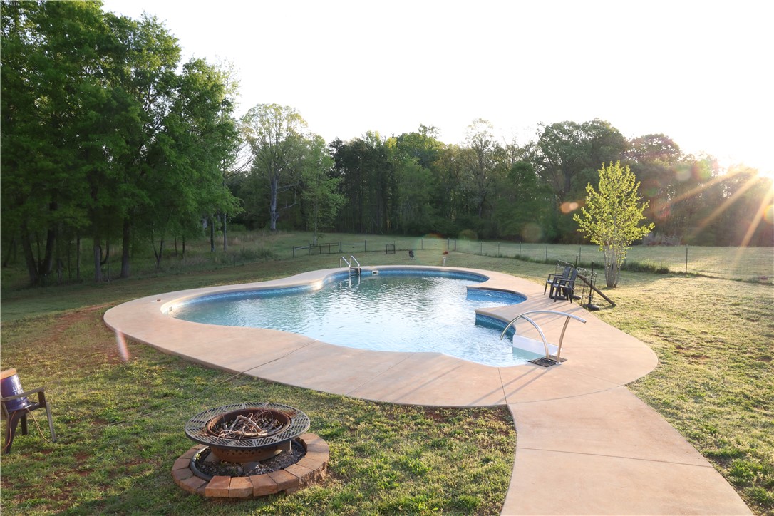 5381 Olden Porter Road Pendleton, SC 29670 - Photo 12 of 31 Enjoy outdoor living with a custom in-ground pool and fire pit, surrounded by lush greenery.