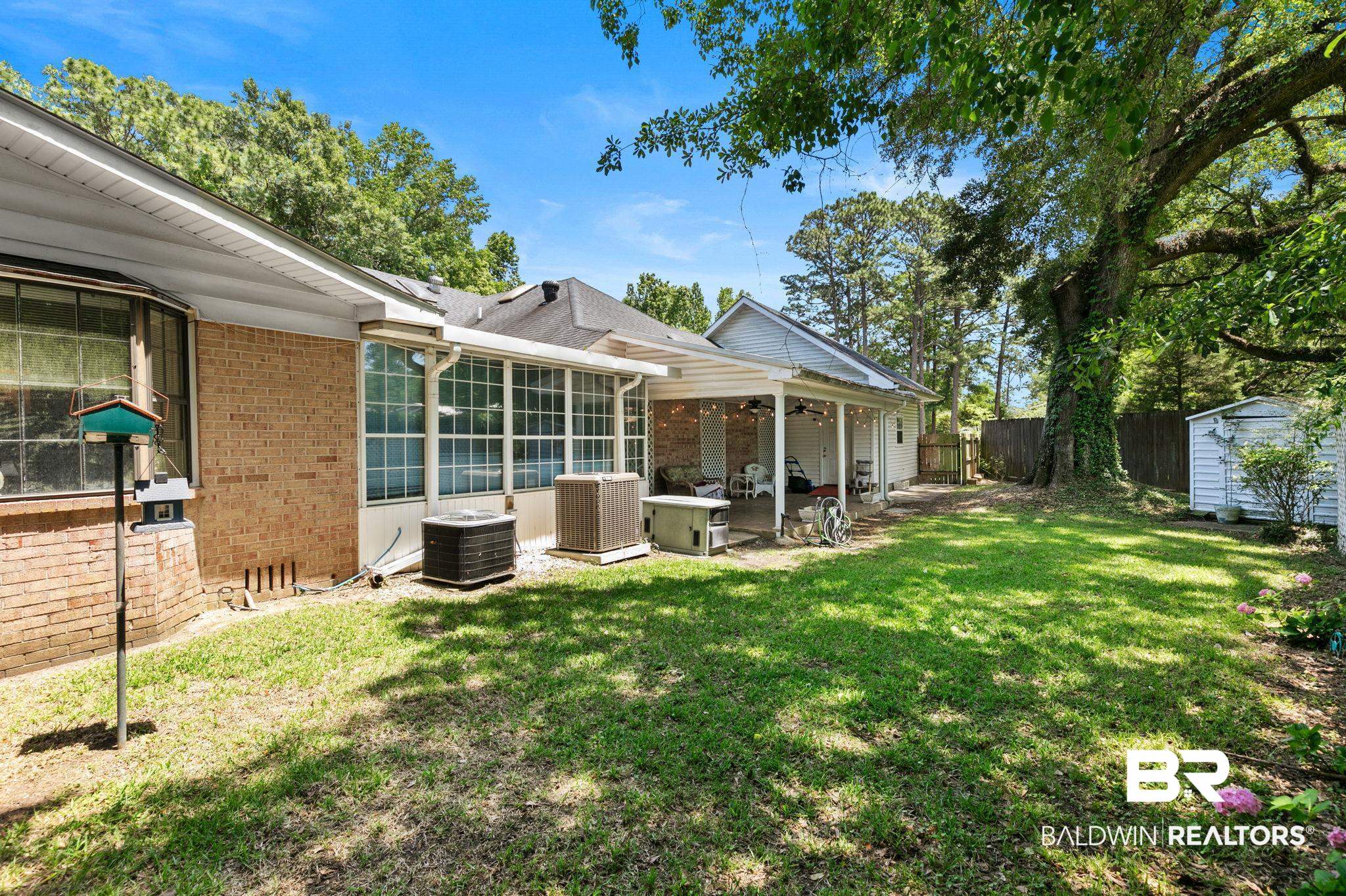 927 Cleveland Road Saraland, AL 36571 - Photo 62 of 80 Expansive backyard featuring a manicured lawn, a large mature tree, and a covered patio area