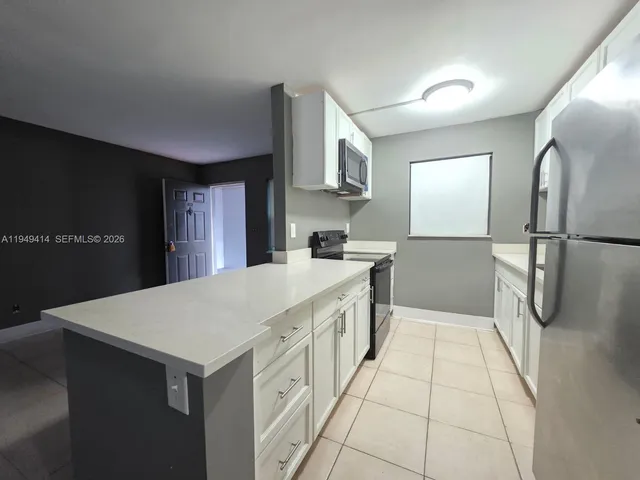 a kitchen with a sink a refrigerator and cabinets