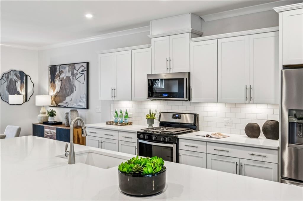 1155 Millennium Park Road Decatur, GA 30033 - Photo 23 of 81 a kitchen with stainless steel appliances a white stove top oven a sink a dining table and chairs