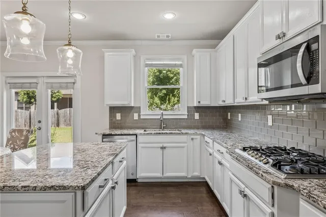 a kitchen with stainless steel appliances granite countertop a stove a sink and a microwave