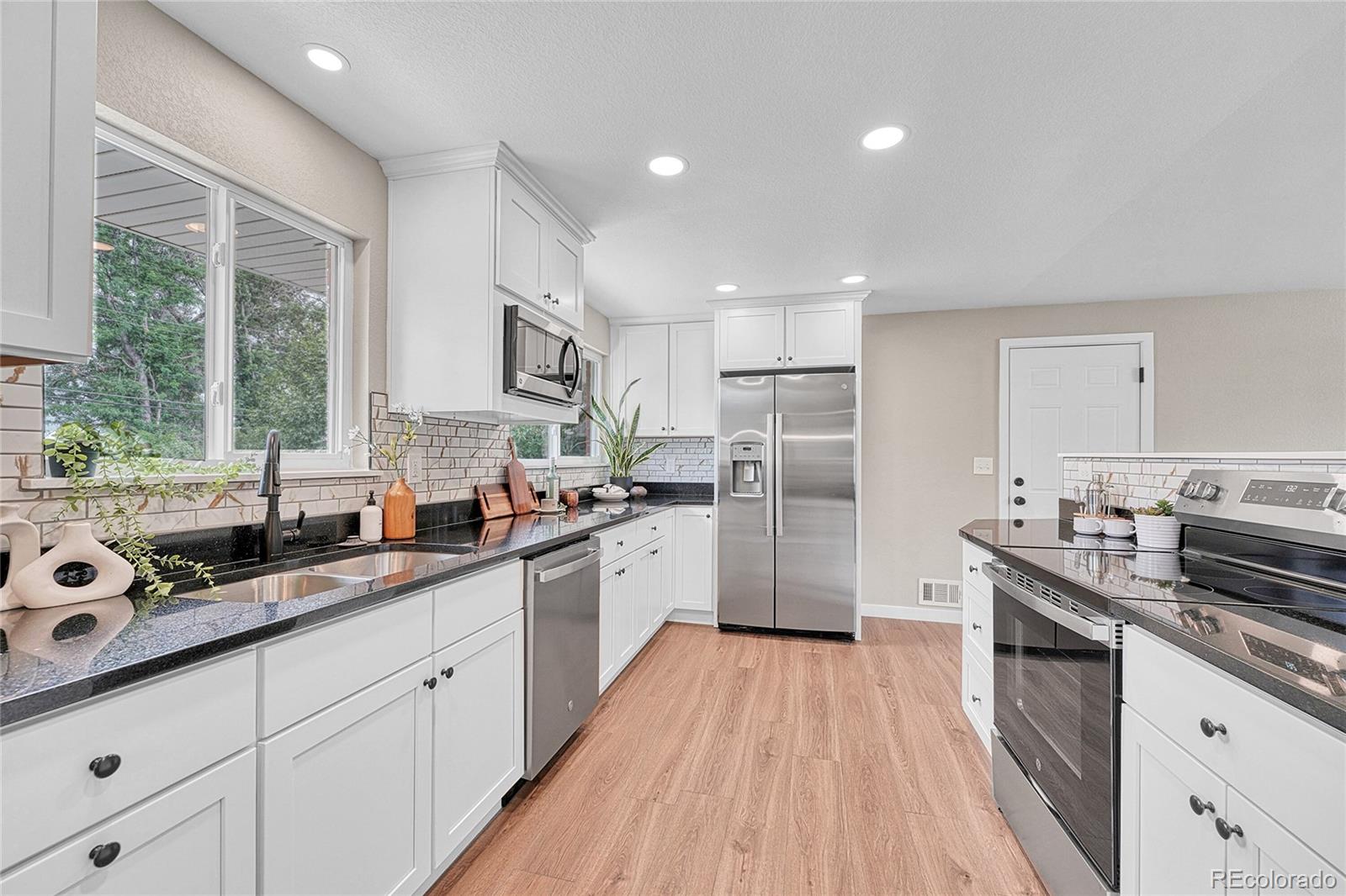 215 East Panama Drive Centennial, CO 80121 - Photo 26 of 50 a kitchen with stainless steel appliances granite countertop a sink cabinets and wooden floor