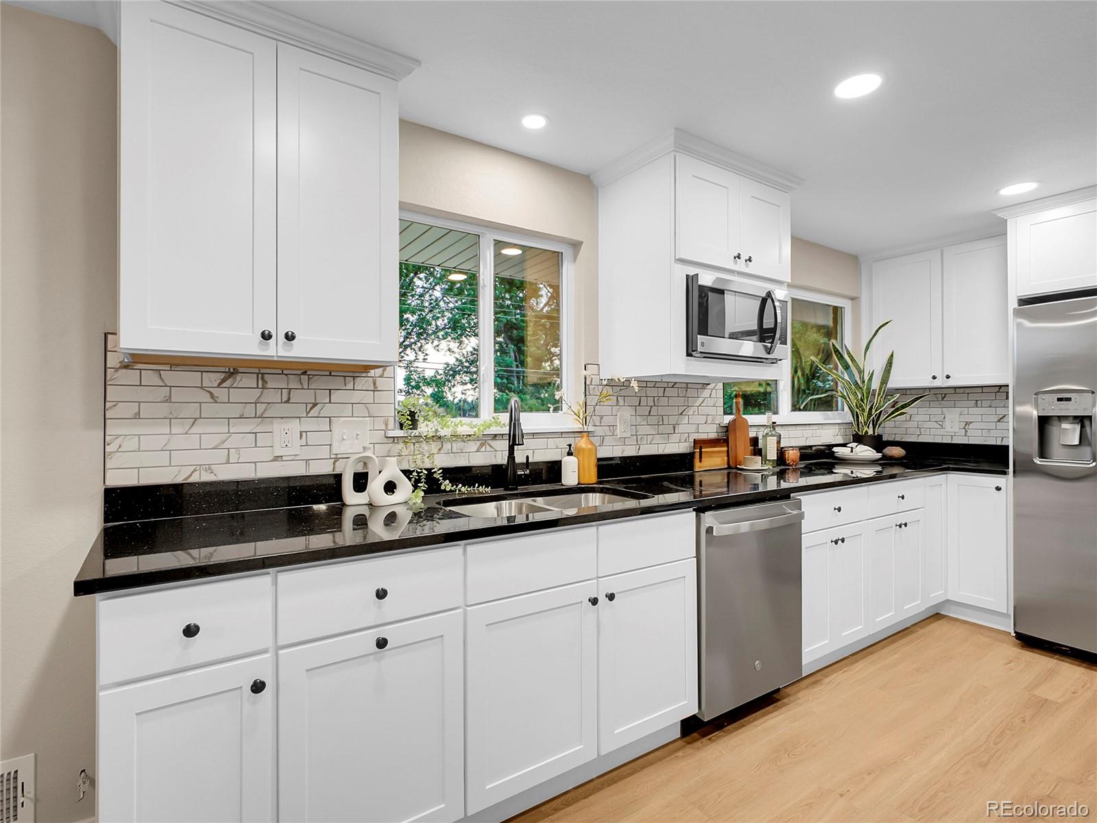 215 East Panama Drive Centennial, CO 80121 - Photo 5 of 50 a kitchen with granite countertop white cabinets white appliances a sink and a window