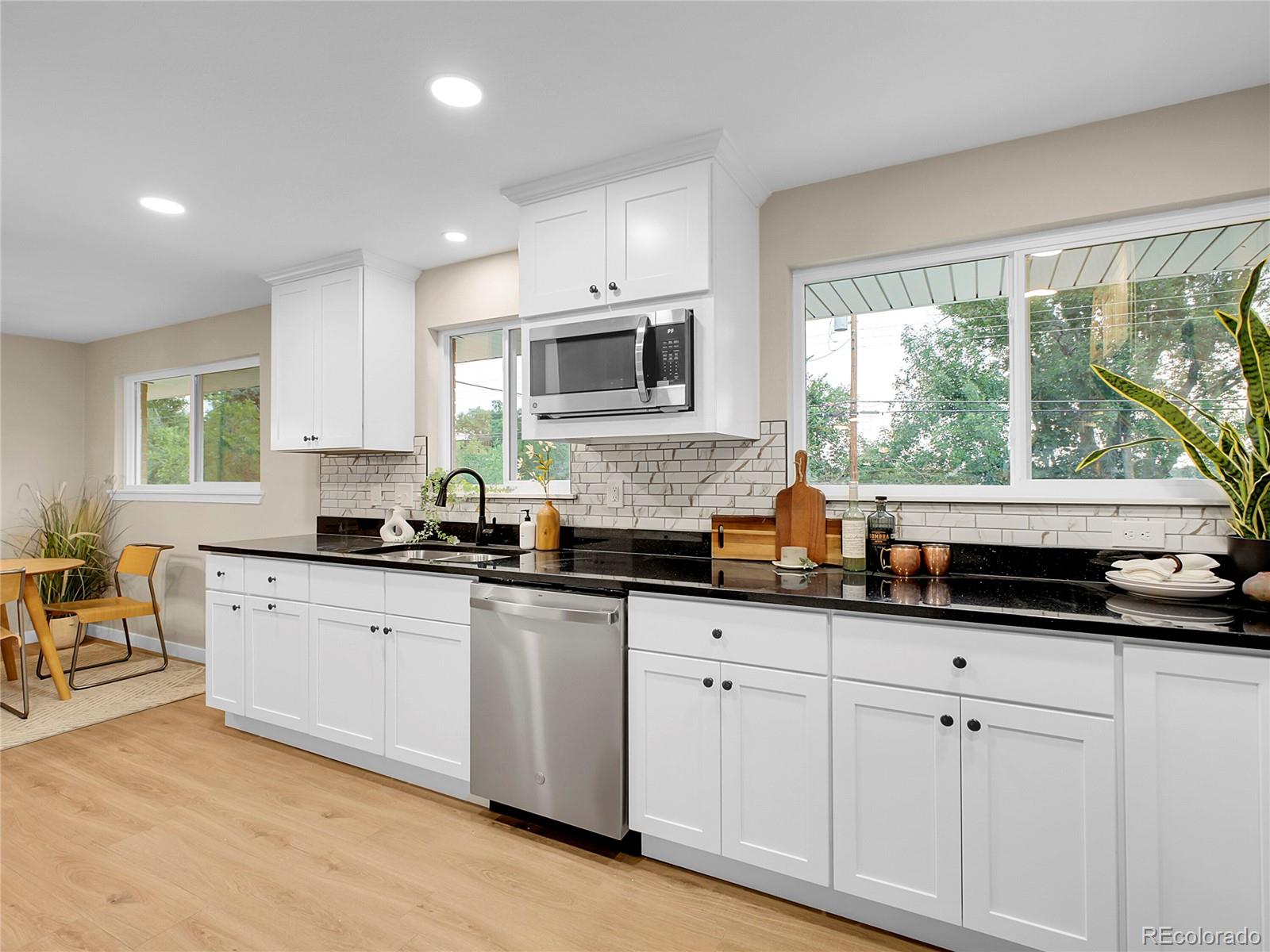 215 East Panama Drive Centennial, CO 80121 - Photo 6 of 50 a kitchen with granite countertop white cabinets a sink a window and stainless steel appliances