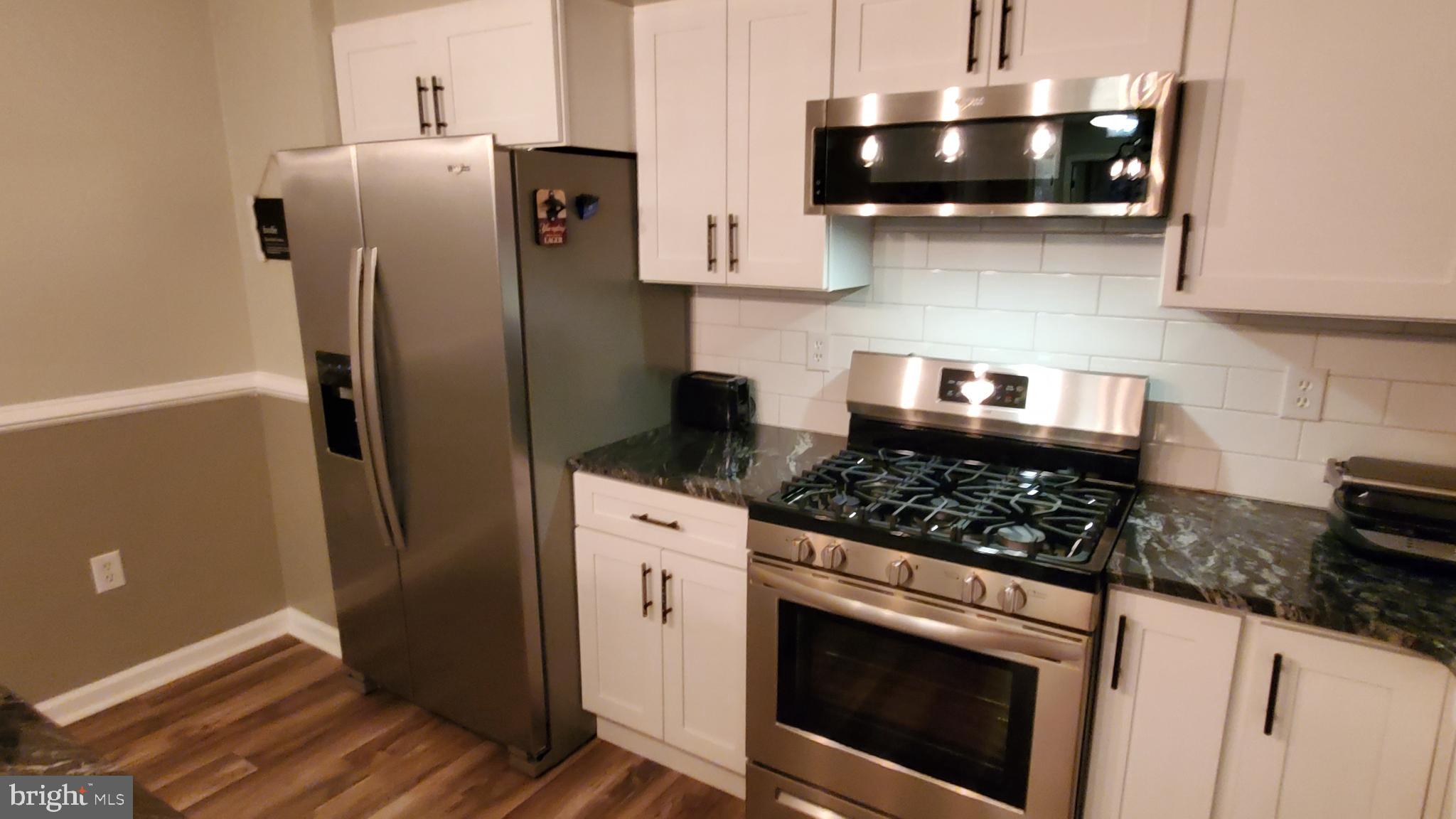 916 Timber Lane Reading, PA 19608 - Photo 8 of 29 a kitchen with stainless steel appliances granite countertop a refrigerator a stove and a sink with wooden floor
