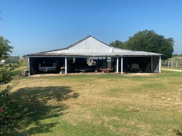 a view of a house next to a yard with plants and large trees