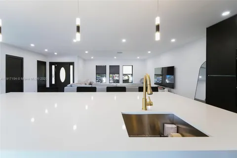 a large kitchen with stainless steel appliances a large counter top a refrigerator and a sink