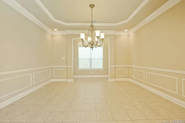 a view of an empty room with chandelier and window