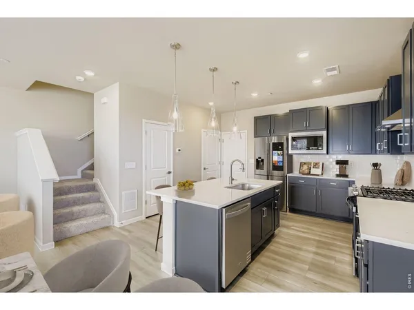 a large kitchen with kitchen island a dining table chairs and white cabinets