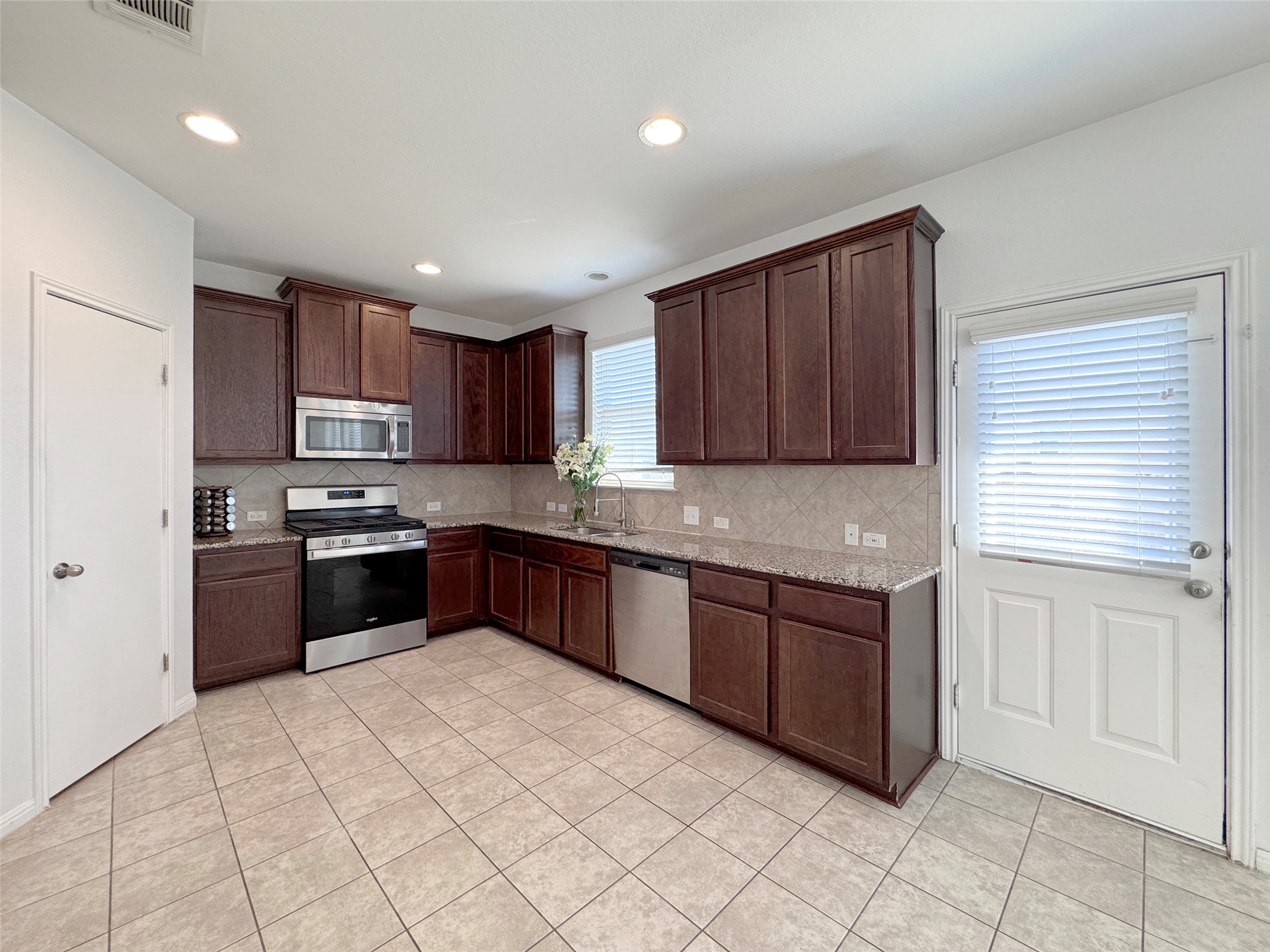 251 Triumph Road Buda, TX 78610 - Photo 8 of 24 Kitchen with stainless steel appliances, dark wood finish cabinetry, light stone counters, light tile patterned floors, and recessed lighting
