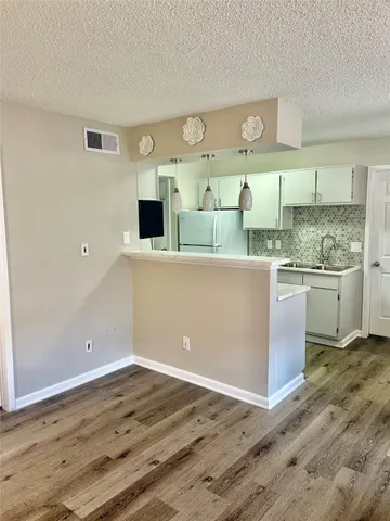 a view of a kitchen with wooden floor and cabinets
