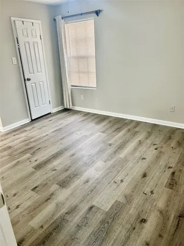 an empty room with wooden floor and window