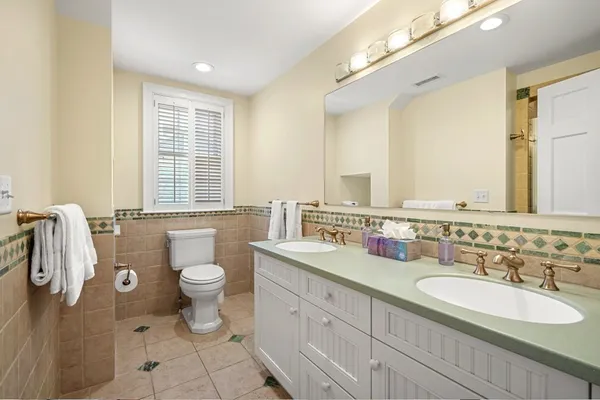 a bathroom with a double vanity sink toilet mirror and bathtub