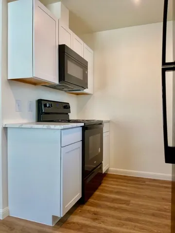 a kitchen with stainless steel appliances white cabinets and a wooden floor